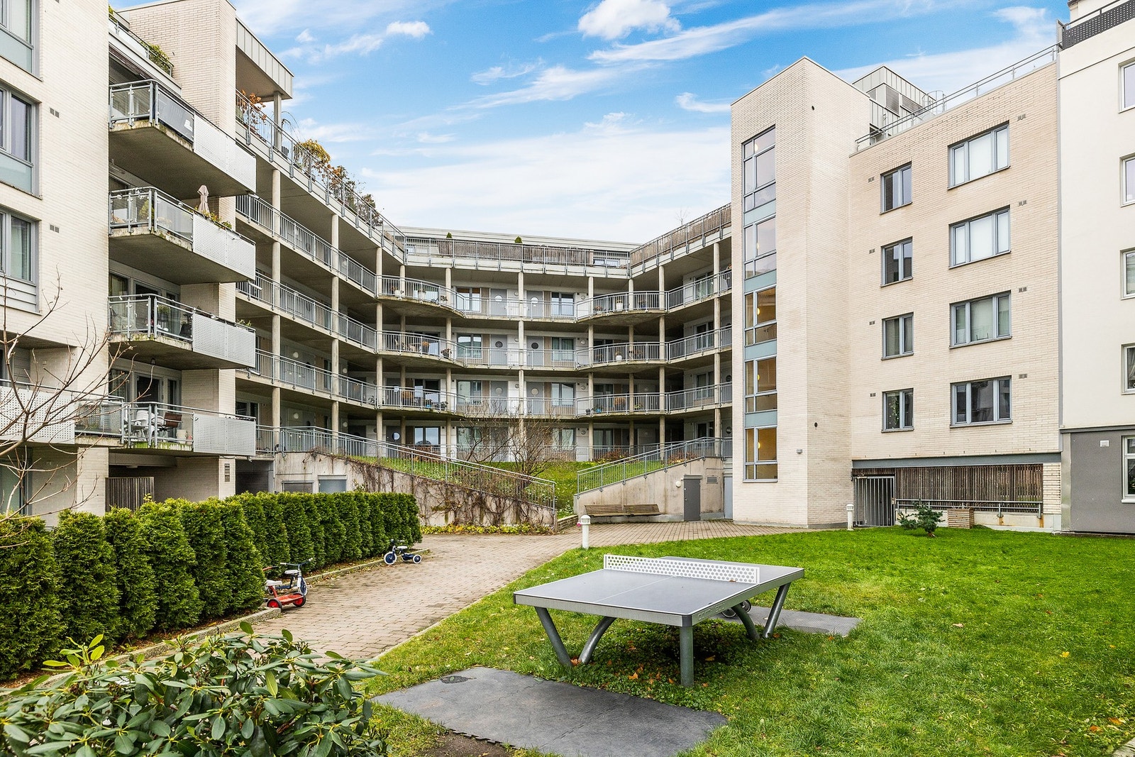 Pen, frodig bakgård med blant annet tennisbord. Galleribilde