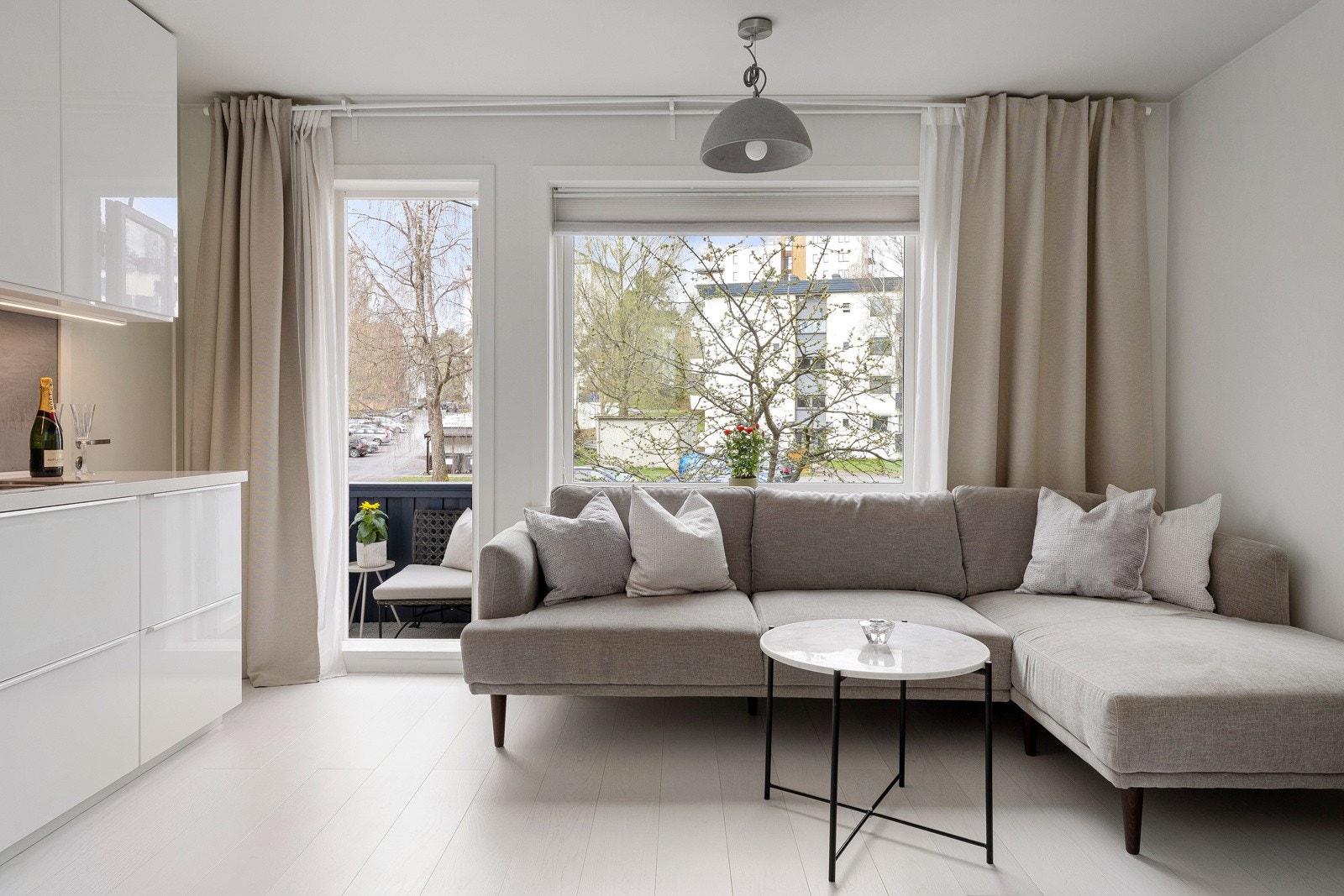 Stuen har et stort vindu og en balkongdør i glass som gir rommet rikelig med naturlig lys og et hyggelig utsyn. Galleribilde