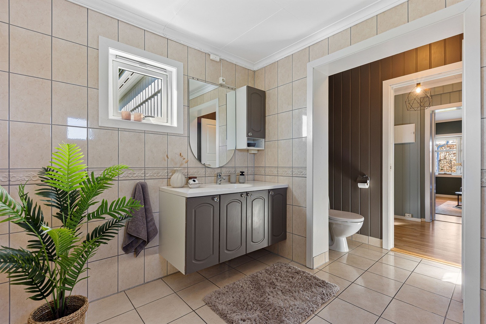 Romslig flislagt bad i delikate farger. Toalett i egen nisje. Galleribilde