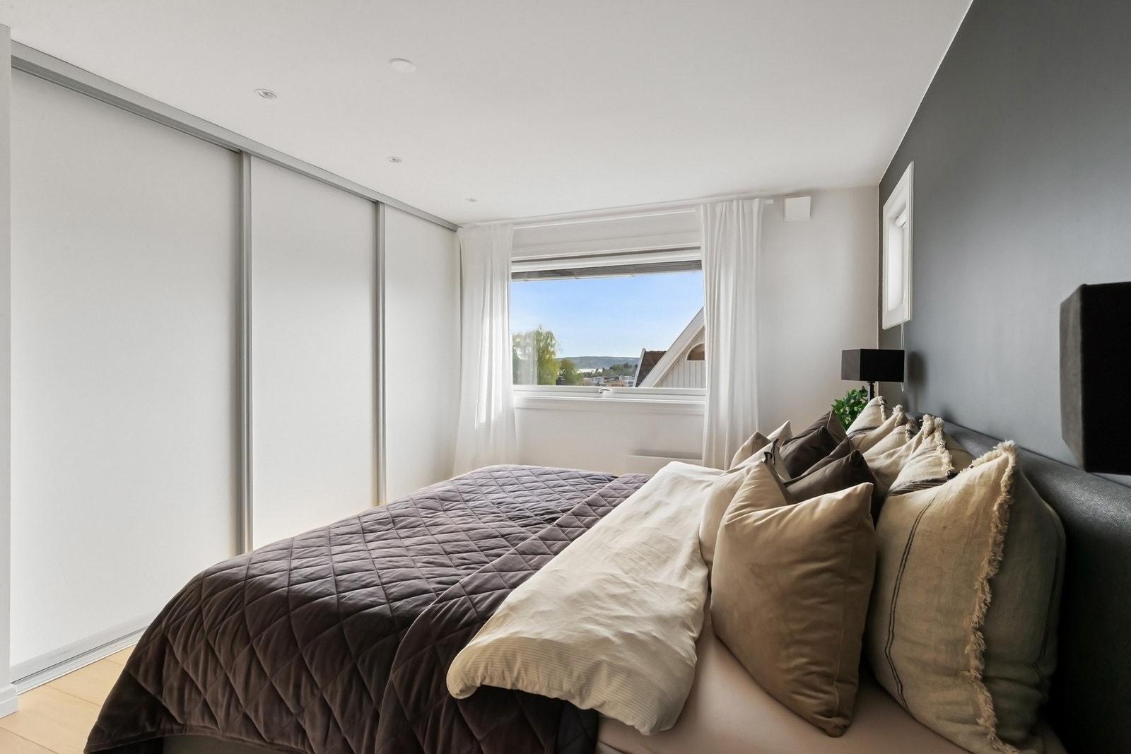 På rommet er det god plass til stor dobbeltseng, nattbord og gode oppbevaringsmuligheter i skyvedørsgarderobe. Galleribilde