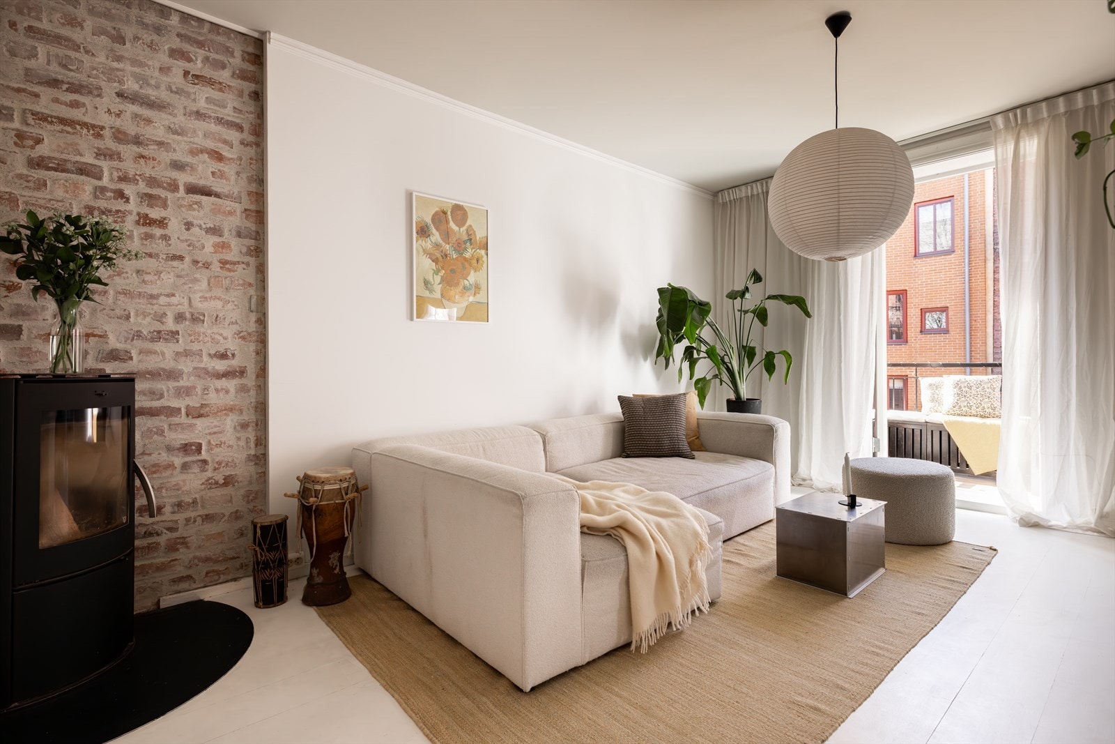 Lys og innbydende stue med malt gulv og glatte, lyse veggflater som gir rommet et stilrent uttrykk. Den karakteristiske teglsteinsveggen bak peisen i stuen skaper en flott kontrast til det ellers lyse interiøret. Galleribilde