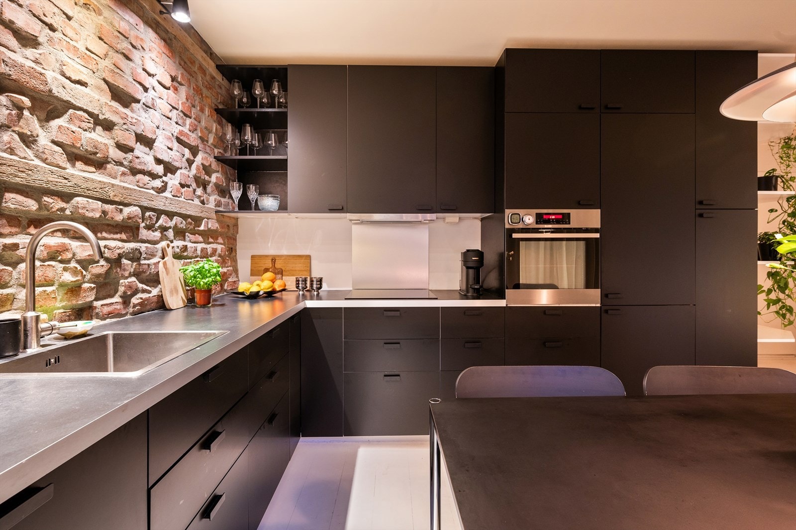 Kjøkkenet har fint belyst teglstensvegg som gir en lekker effekt på kveldstid. Det er svært god skap- og benkeplass på kjøkkenet Galleribilde