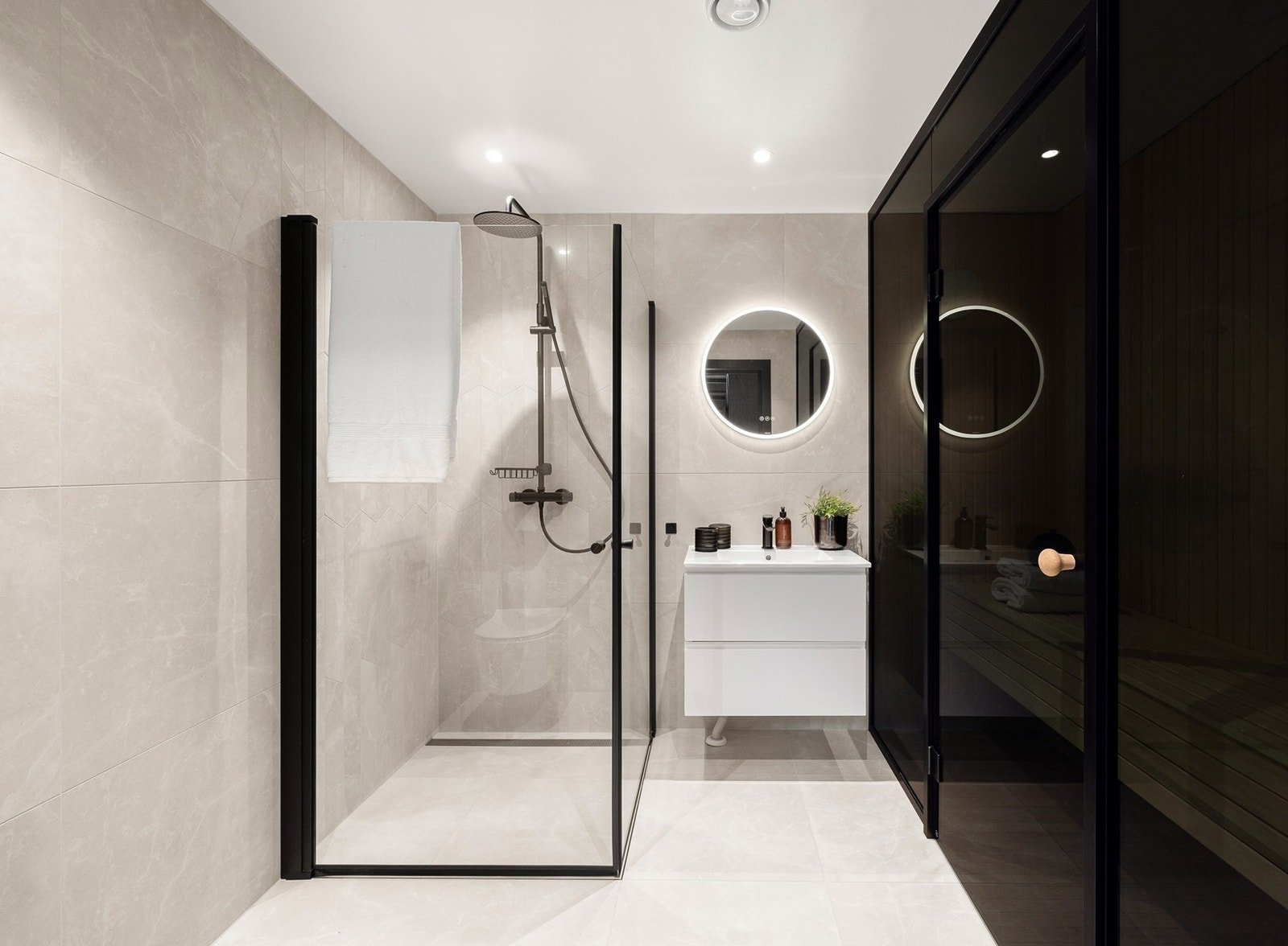 Et lyst og lekkert bad med tilgang til badstue. Badet har lyse fliser på gulv og vegger, gulvvarme og downlights i himling. Galleribilde