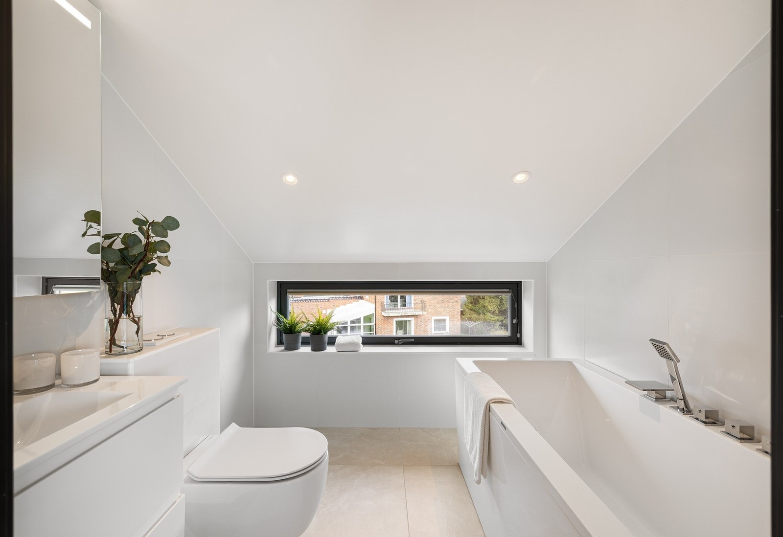 Et lyst og luftig bad med lyse fliser på gulv og vegger. Innredningen består av underskap/overskap, servant, speil, stikk og ett badekar. Videre har badet gulvvarme, downlights i himling og vegghengt vannklosett. Galleribilde