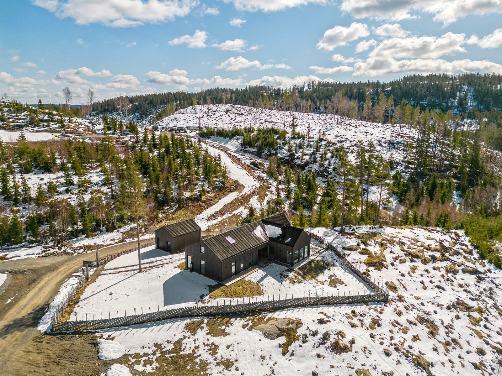 Det er satt opp skigard som rammer inn eiendommen. Gruset innkjørsel med dobbel port. Galleribilde