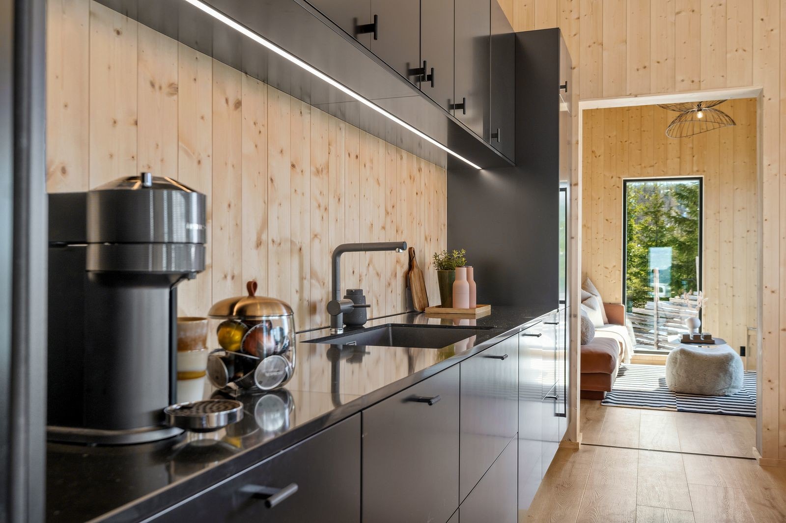 Innredningen består av mørke slette skuffe- og skapfronter og benkeplate i lekker quarts som tåler både høy varme og som er motstandsdyktig mot flekker. Vaskekummen er underlimt og i sort kompositt. Galleribilde