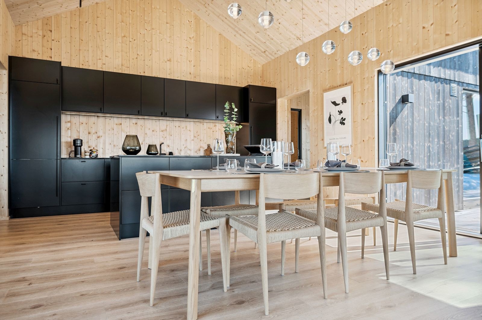 Stilrent kjøkken i åpen løsning, plassert midt i hjertet av fritidsboligen. Kjøkkenet er praktisk innredet med en stor frittstående kjøkkenøy og fremstår som meget innbydende. Galleribilde