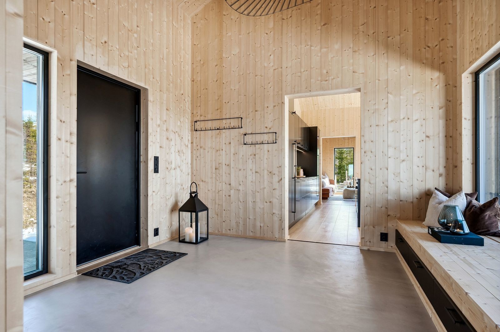 Romslig hall med flott takhøyde, stilren mikrosement på gulv og et stort panoramavindu m/nydelig utsikt - gir et særdeles godt førsteinntrykk av fritidsboligen. Veggflatene og himling er holdt i ubehandlet granpanel. Galleribilde
