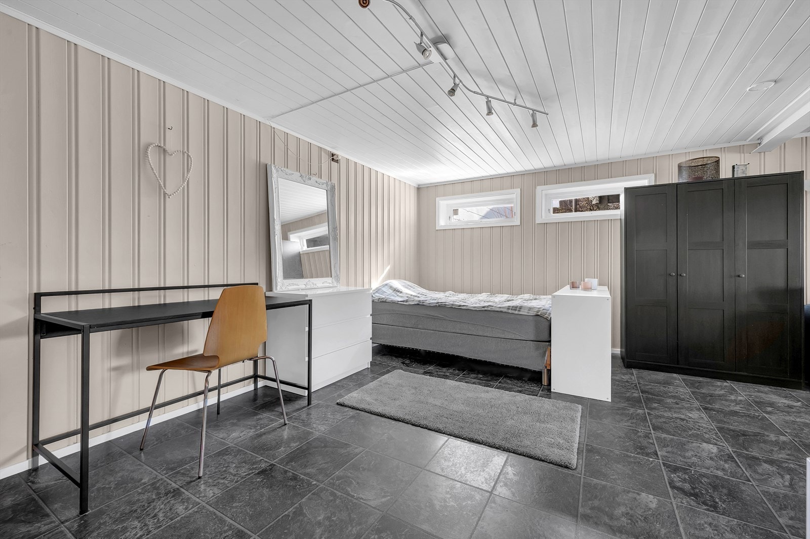 Gulvet er belagt med laminat, og veggene er kledd med malt panel i lune fargetoner, som gir en varm og innbydende atmosfære. Galleribilde