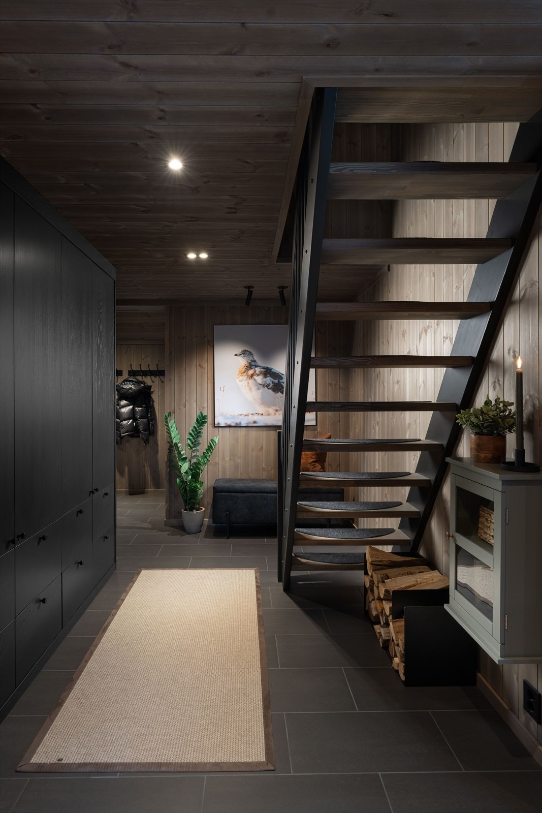 Romslig gang med plass for yttertøy og utstyr på knagger og i plassbygde skap. Praktisk flislagt gulv med varme under, og trapp opp til hems. Galleribilde