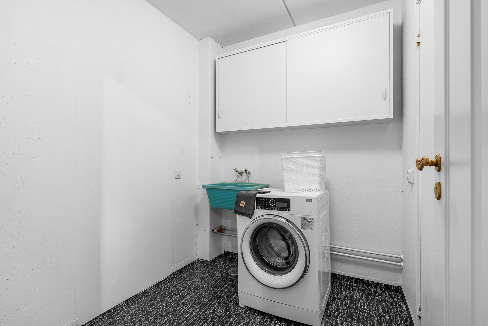 Praktisk vaskerom med belegg på gulv, veggene har malt strie, noe veggskap og det er malt himling. Vaskerommet består videre av opplegg for vaskemaskin og utslagsvask.! Galleribilde