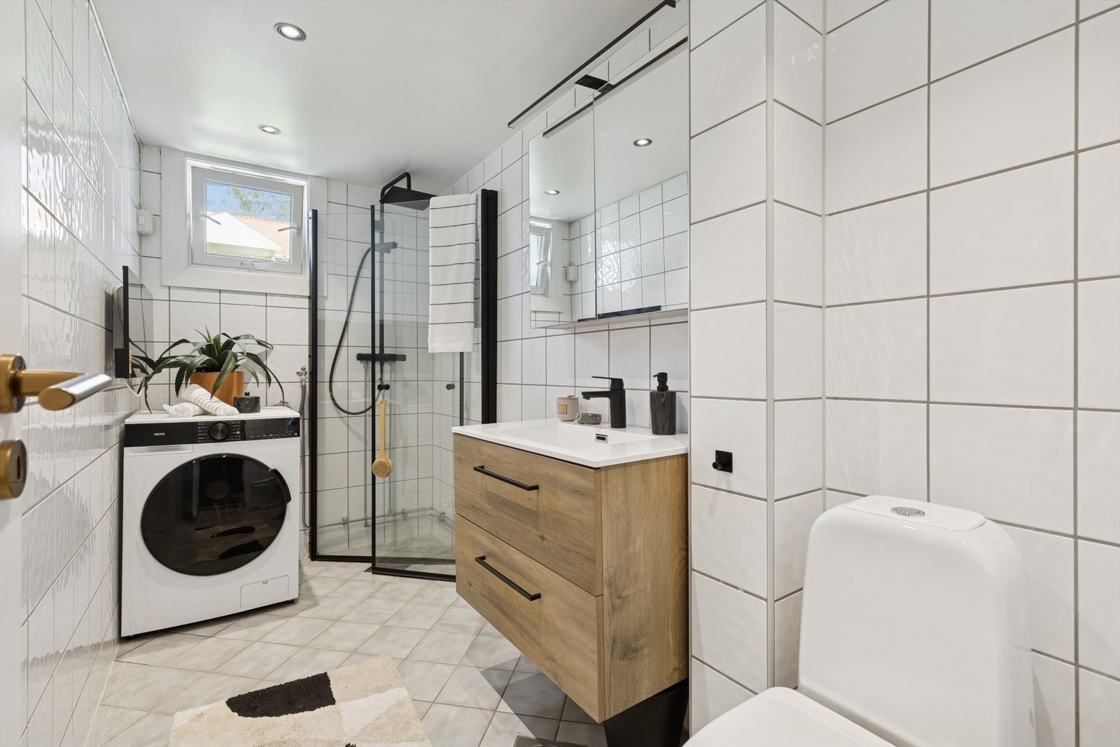 Baderommet er utstyrt med innredning som inkluderer en nedfelt servant, toalett, og praktiske dusjvegger/hjørne. Det er også opplegg for vaskemaskin, noe som gjør det enkelt å håndtere klesvasken. Galleribilde