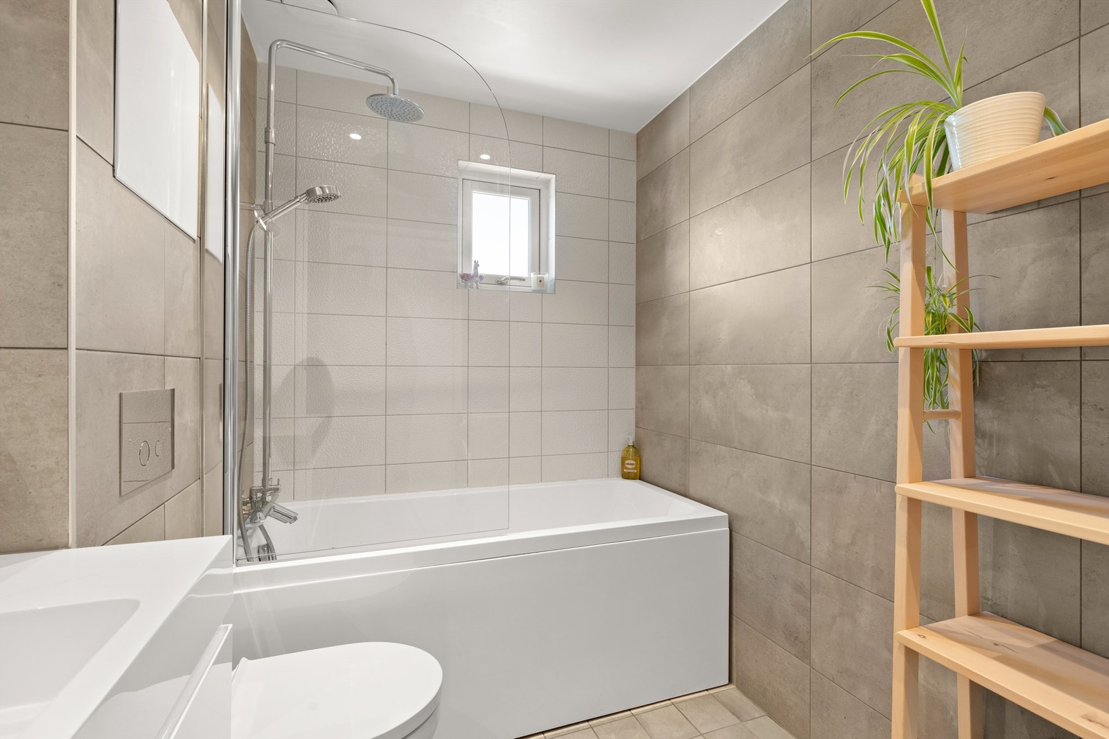 Badet er utrustet med vegghengt servantinnredning med skuffer, heldekkende servant, speilskapet, vegghengt skap for oppbevaring, badekar, vegghengt toalettet og opplegg for vaskemaskin og tørketrommel. Galleribilde
