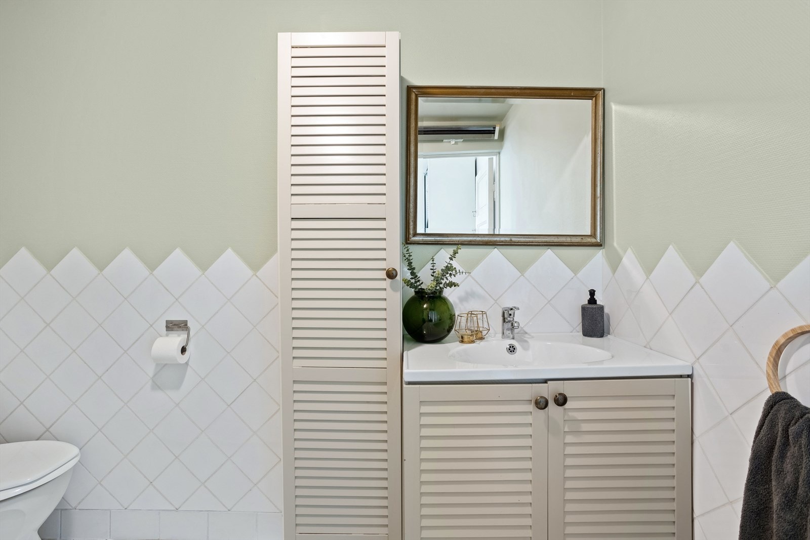 Badet er innredet med håndvask med underskap, dusjkabinett og gulv montert wc. Leiligheten har eget vaskerom i kjeller med opplegg til vaskemaskin. Galleribilde