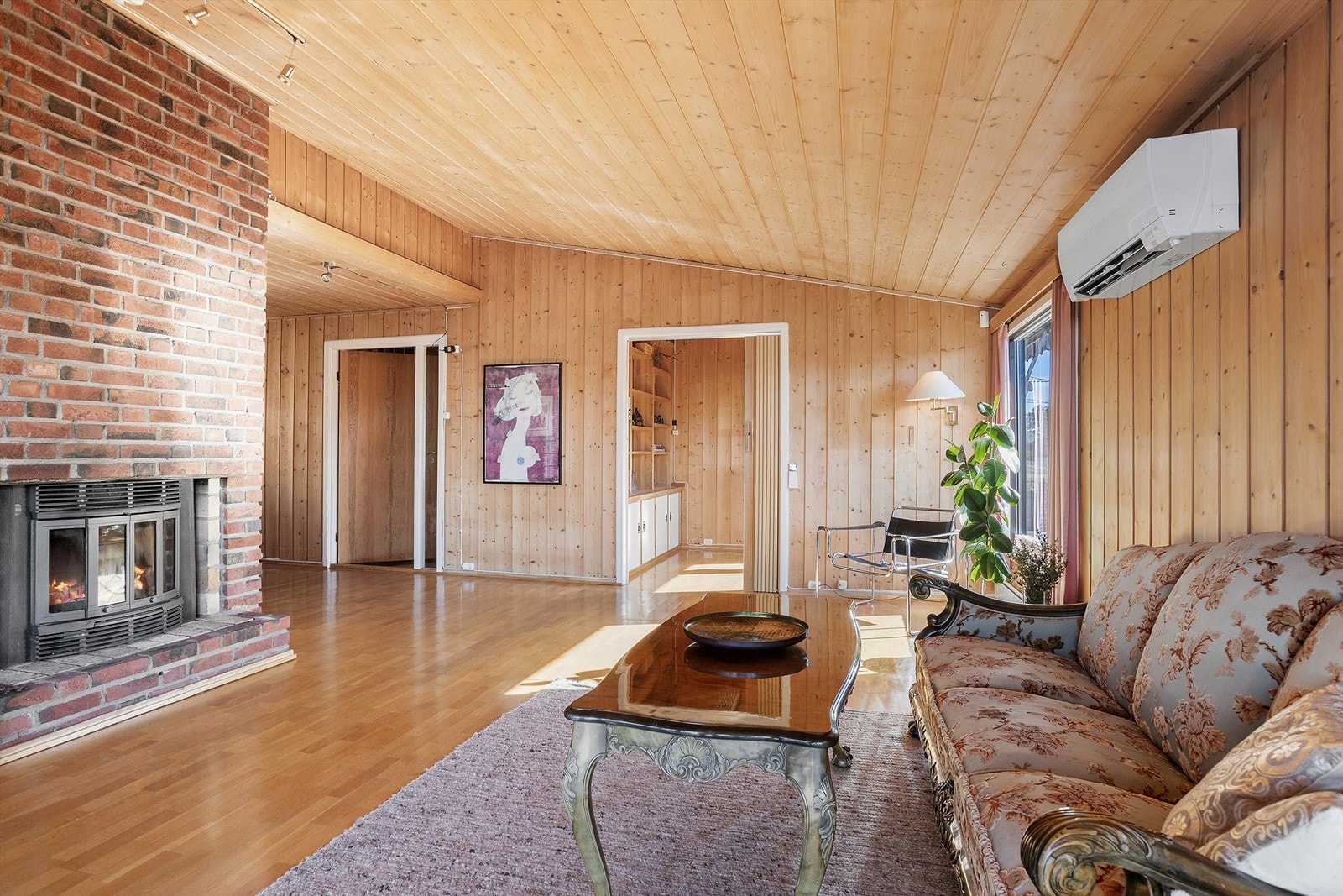 Hyggelig stue med god takhøyde og parkettgulv. En av veggene i stuen er av teglstein og har peis. Galleribilde