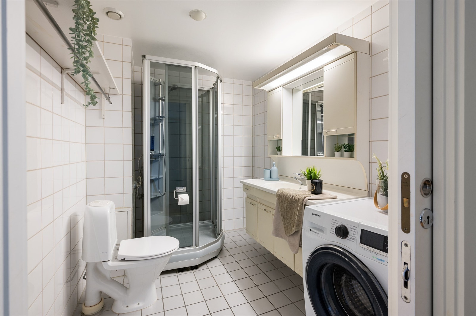 Romslig flislagt baderom med gulvvarme og opplegg for vaskemaskin Galleribilde