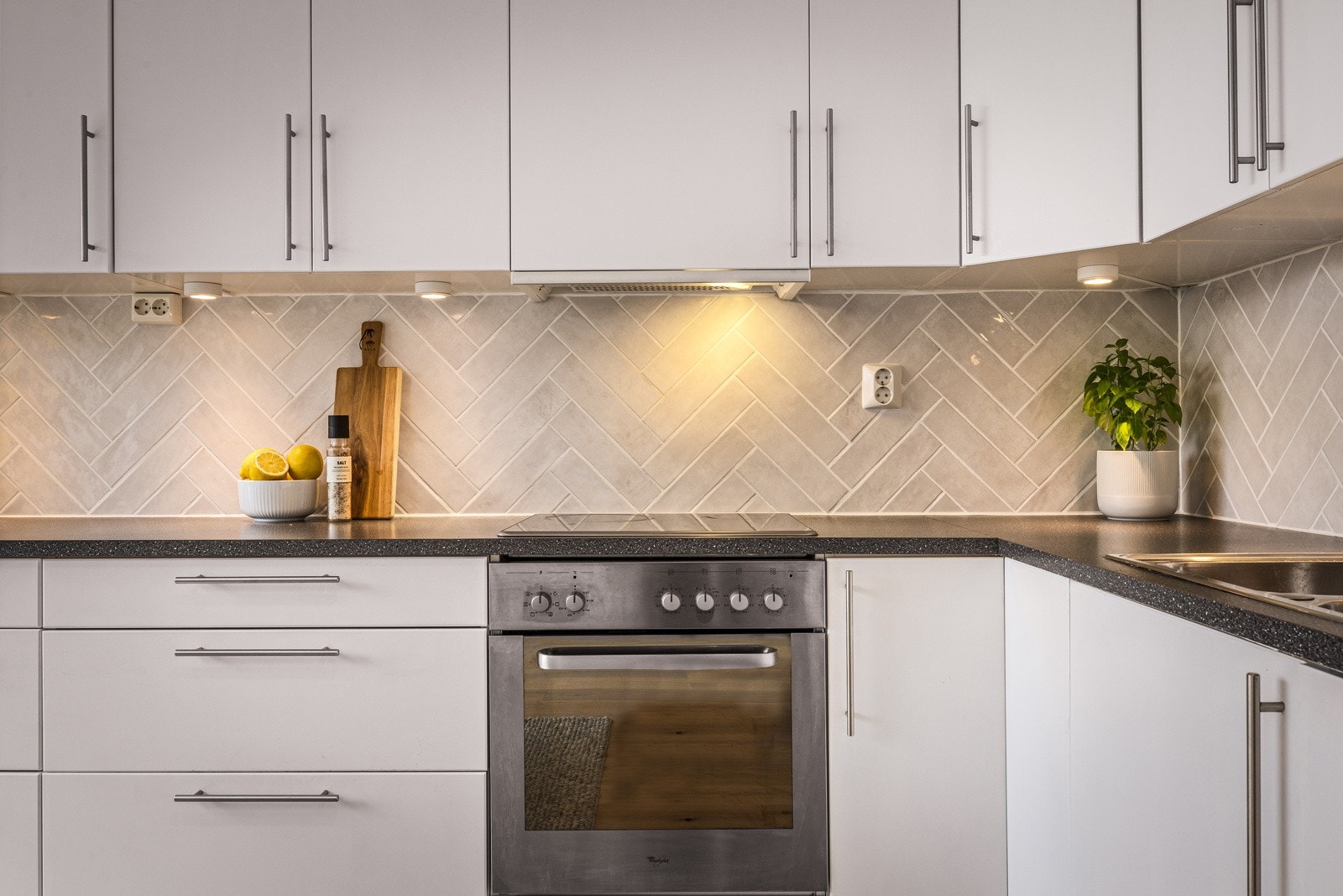 Lekre fliser i fiskebensmønster mellom overskap og benkeplate Galleribilde