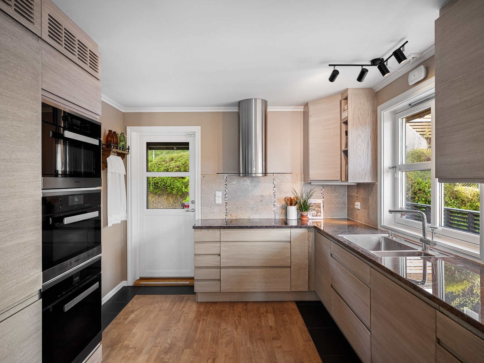 Velutstyrt og i arbeidshøyde. Enkelt å ta maten ut på fine dager. Et moderne Huseby kjøkken med flere vindu for naturlig lys, og spotter under overskap for kvelden. Galleribilde