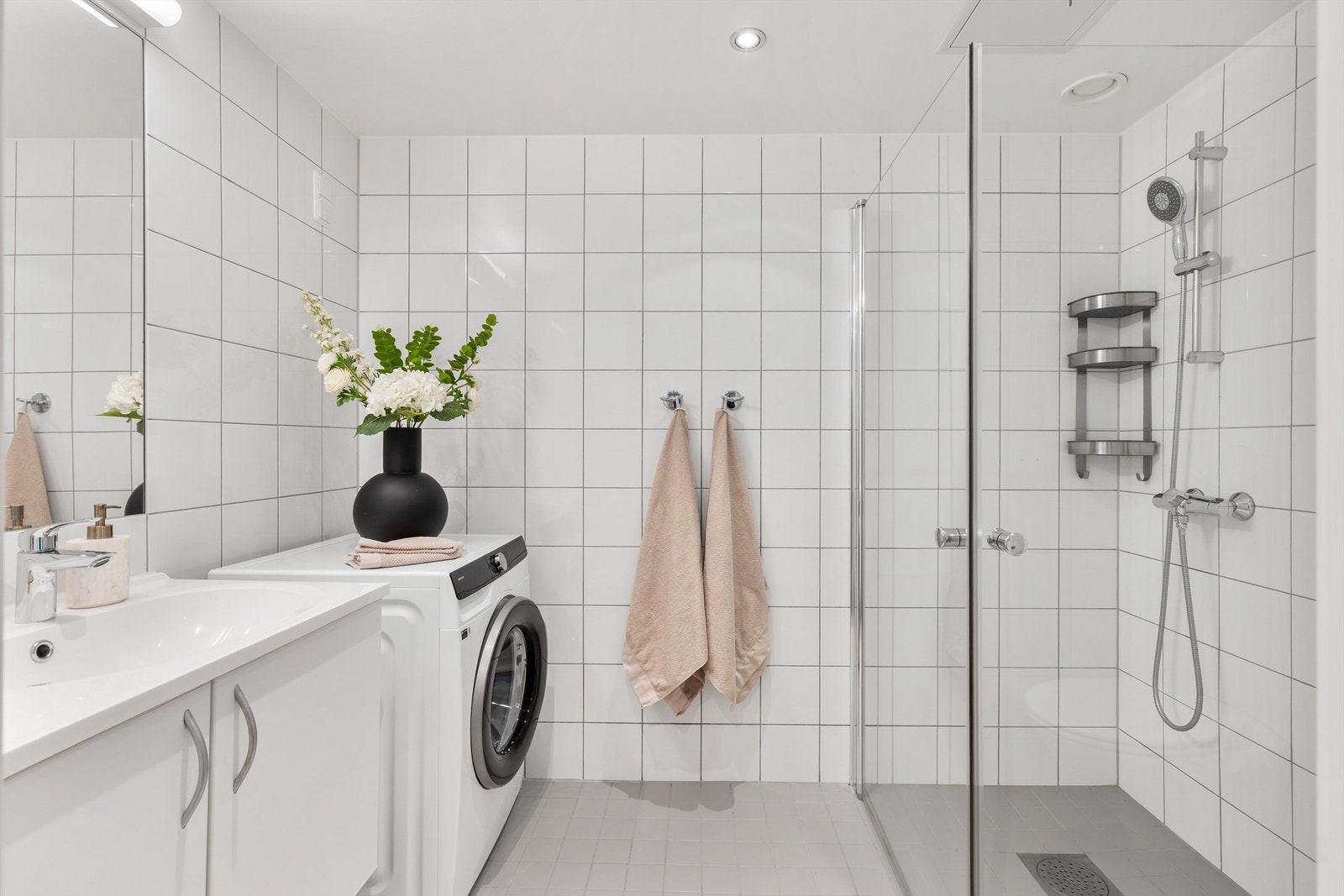 Badet er innredet med vegghengt klosett, servant nedfelt i innredning, speil med lys og dusjhjørne med svingbare glassdører. Galleribilde