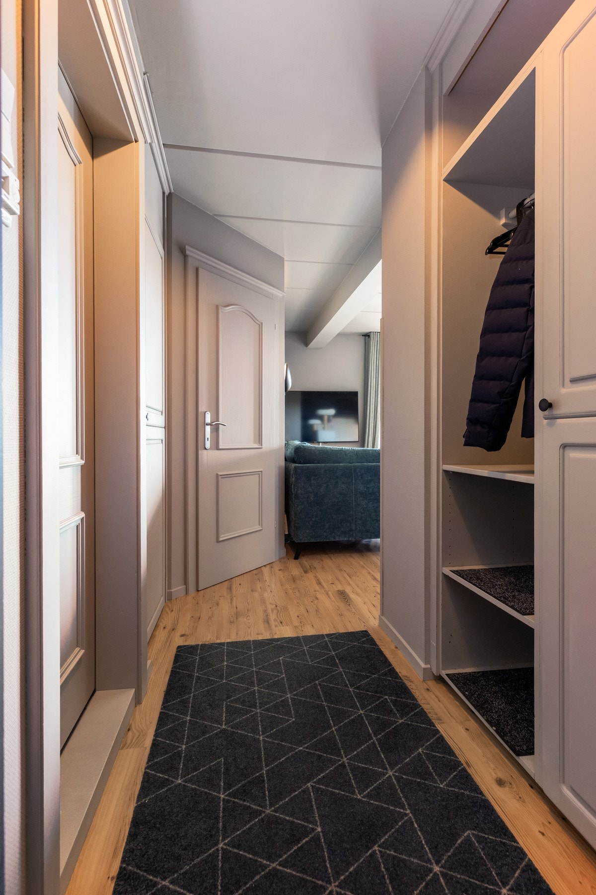 Entré med stedbygd garderobe med hyller, stang og skap hvor det er montert fryseskap Galleribilde