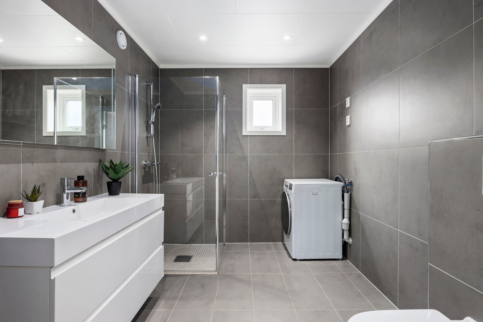 Badet i 2. etasje er stilrent med flislagt gulv og vegger, vegghengt toalett, dusjnisje, vask og opplegg for vaskemaskin. Galleribilde