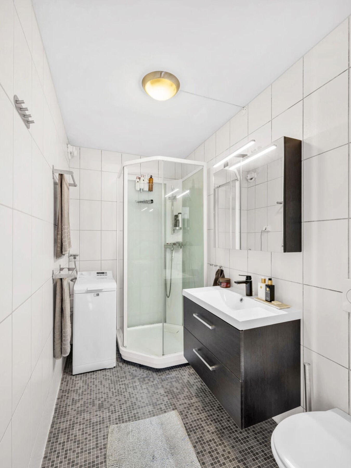 Flislagt bad fra 2006 med opplegg til vaskemaskin og et dusjkabinett som sikrer trygg avrenning til sluk. Her er det også varme i gulv. Galleribilde