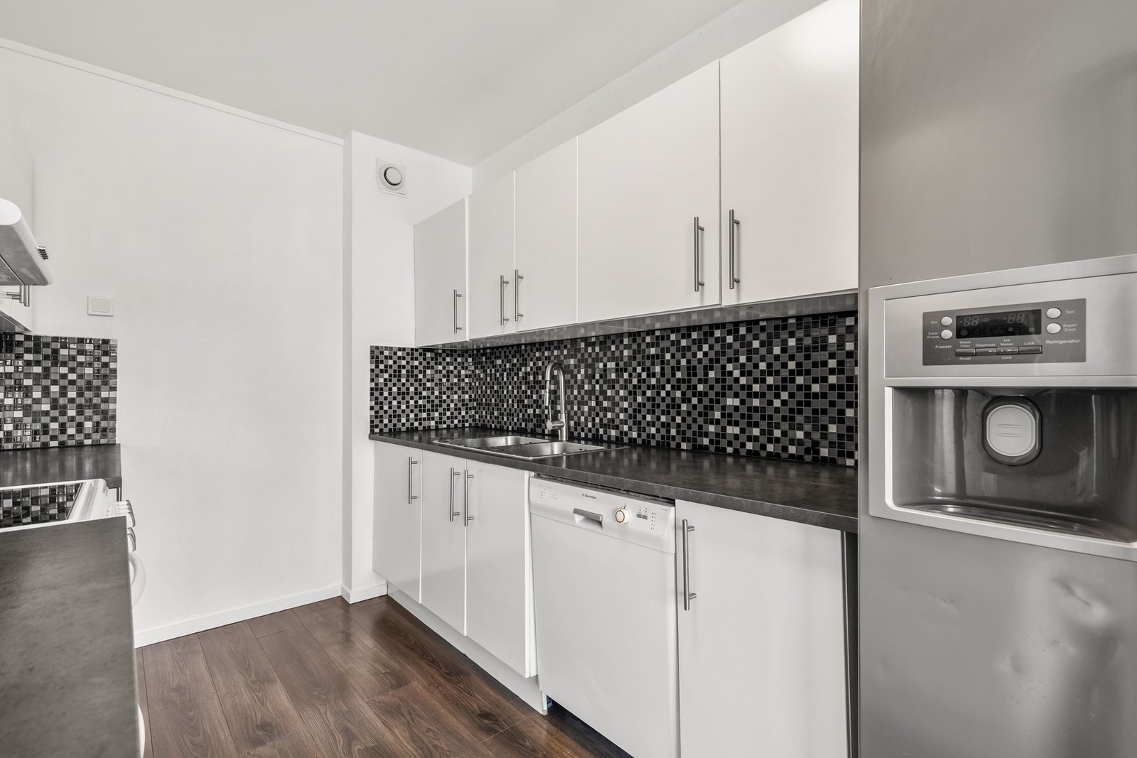 Det er fliser mellom benk og overskap, samt nisje for oppvaskmaskin under benk Galleribilde