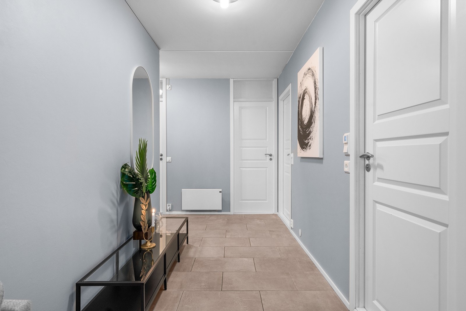 Entreen/gangen fungerer som et praktisk knutepunkt for flere av rommene i leiligheten. Rommet har tidsriktige, lyse fliser på gulv, malte flater på vegger og malt himling! Galleribilde