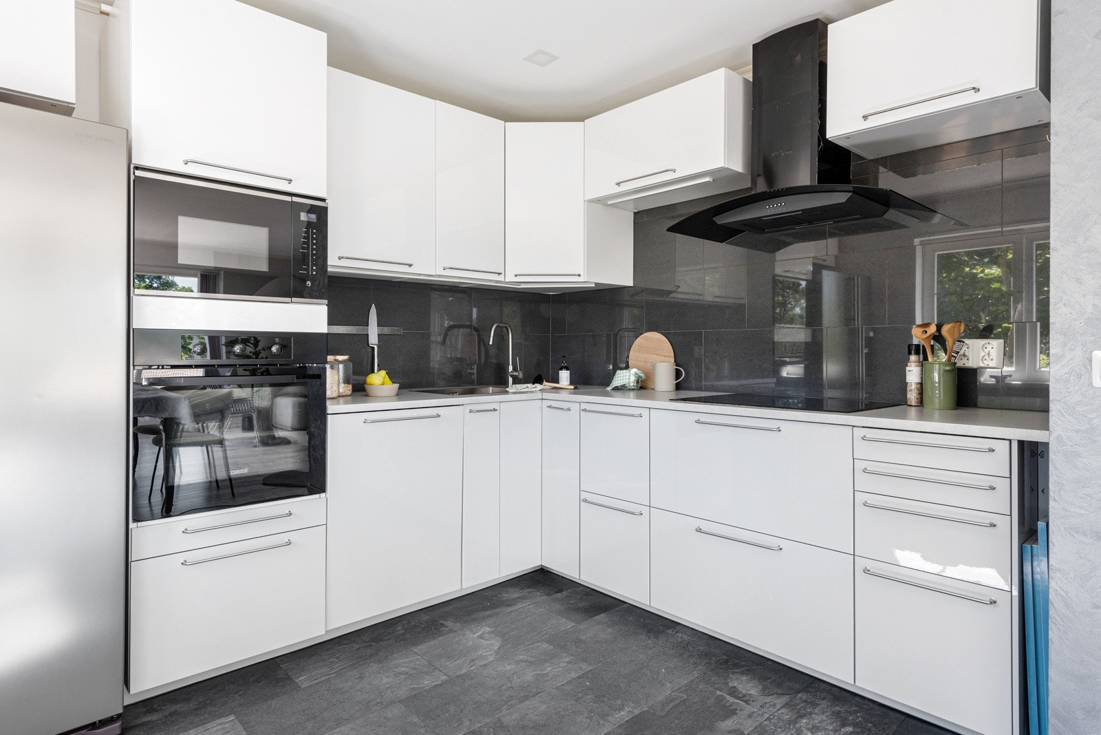 Kjøkkeninnredningen er fra 2018 og har hvite høyglansfronter. Hvitevarer som induksjonstopp, stekeovn, mikrobølgeovn og oppvaskmaskin er integrert. Sort ventilator fra 2023 over koketopp og nisje til kjøleskap. Galleribilde