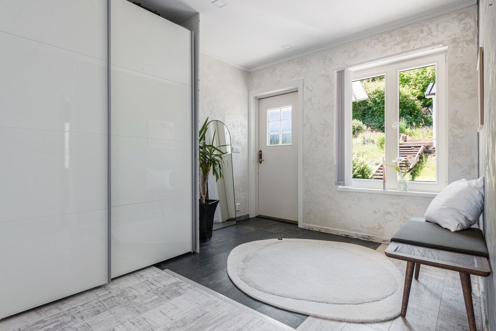 lys tapet på veggene, et flislagt felt med sorte fliser ved inngangspartiet og enstavs laminatgulv i grå og hvite nyanser for øvrig. Galleribilde