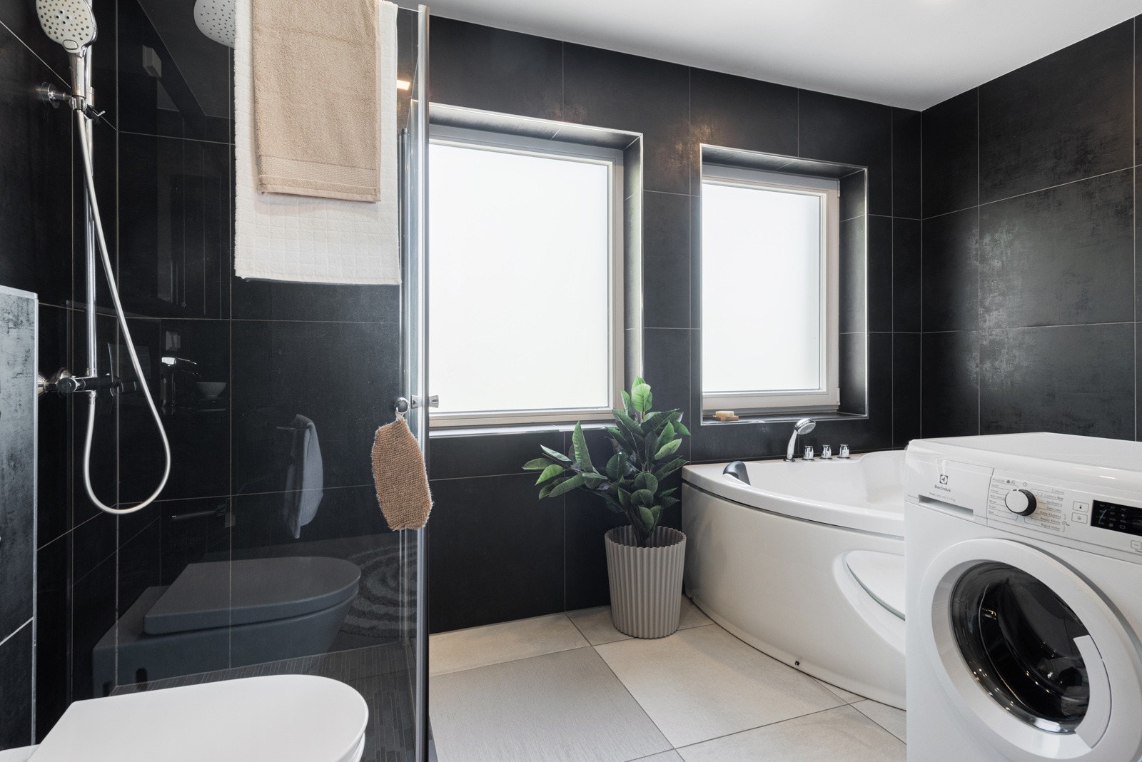 Det er gulvvarme, downlights og vegghengt toalett. I nedsenket dusjhjørne er det grå mosaikkfliser, samt regndusj og hånddusj bak rette, innfellbare glassdører. Galleribilde