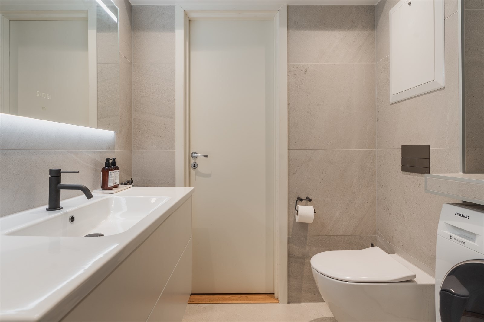Badet er innredet med benkeskap med glatte fronter og servant i helstøpt plate, veggfestet klosett, samt egen nedfelt dusjsone. Galleribilde