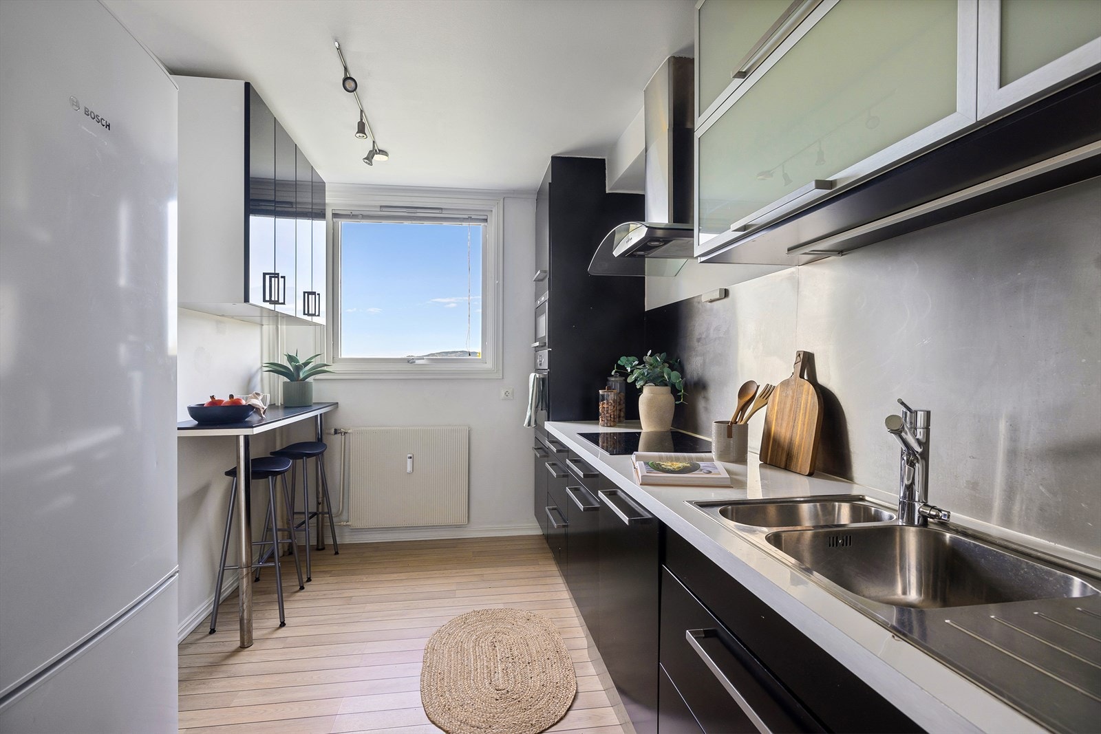 Kjøkkeninnredning med sorte, glatte fronter og benkeplate i laminat med kum og ett-greps blandebatteri. Galleribilde