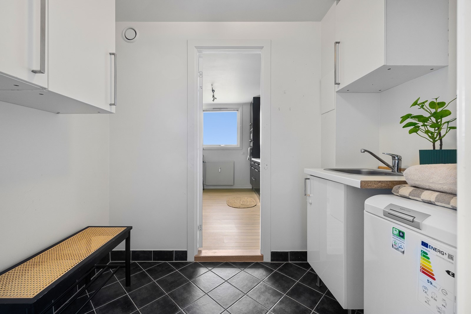 Et flott og praktisk vaskerom som inneholder skapinnredning, servant i rustfritt stål og ett-greps blandebatteri, nedfelt i laminat benkeplate. Her har man opplegg for vaskemaskin og plass til tørketrommel. Galleribilde