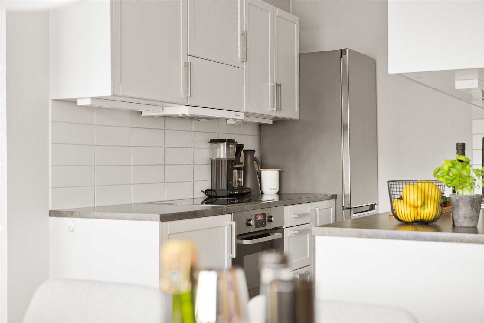 Stilrene hvite fliser som beskytter veggene mellom benk og overskap. Galleribilde