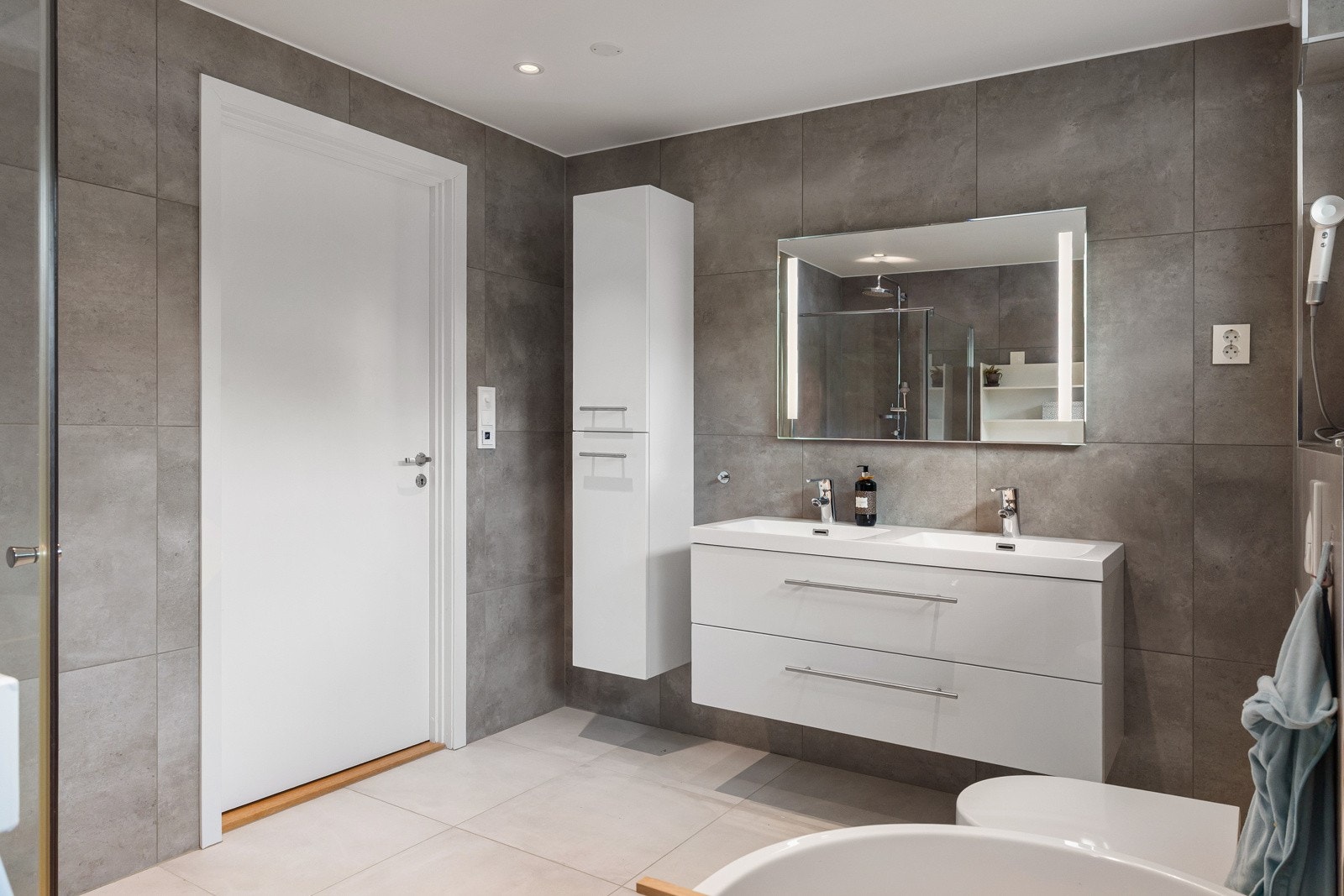 Flislagte gulv med elektriske varmekabler gir ekstra komfort, og veggene er helfliset. Videre er det opplegg for vaskemaskin. Galleribilde