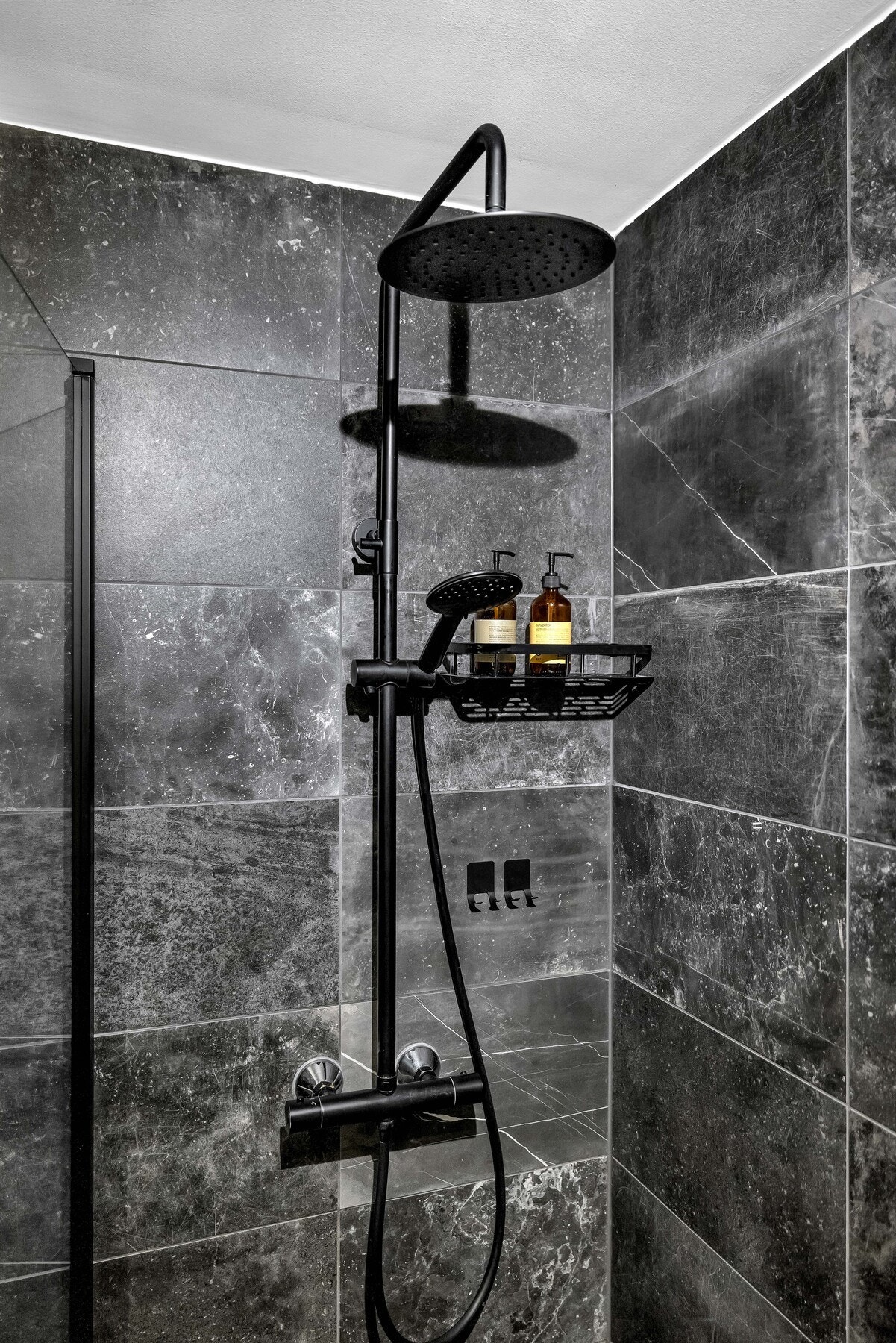 Baderommet utstyrt med overliggende servant med ett-greps armatur, gulvstående toalett, dusjhjørne med innfellbare glassdører og vegghengt dusjarmatur tilkoblet hånddusj og regndusj. Galleribilde