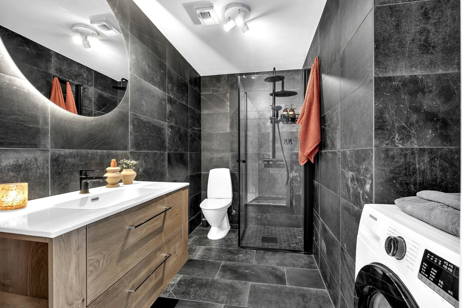 Badet er delikat innredet med mørke fliser på gulv og vegger, og elektriske varmekabler i gulvet. Galleribilde