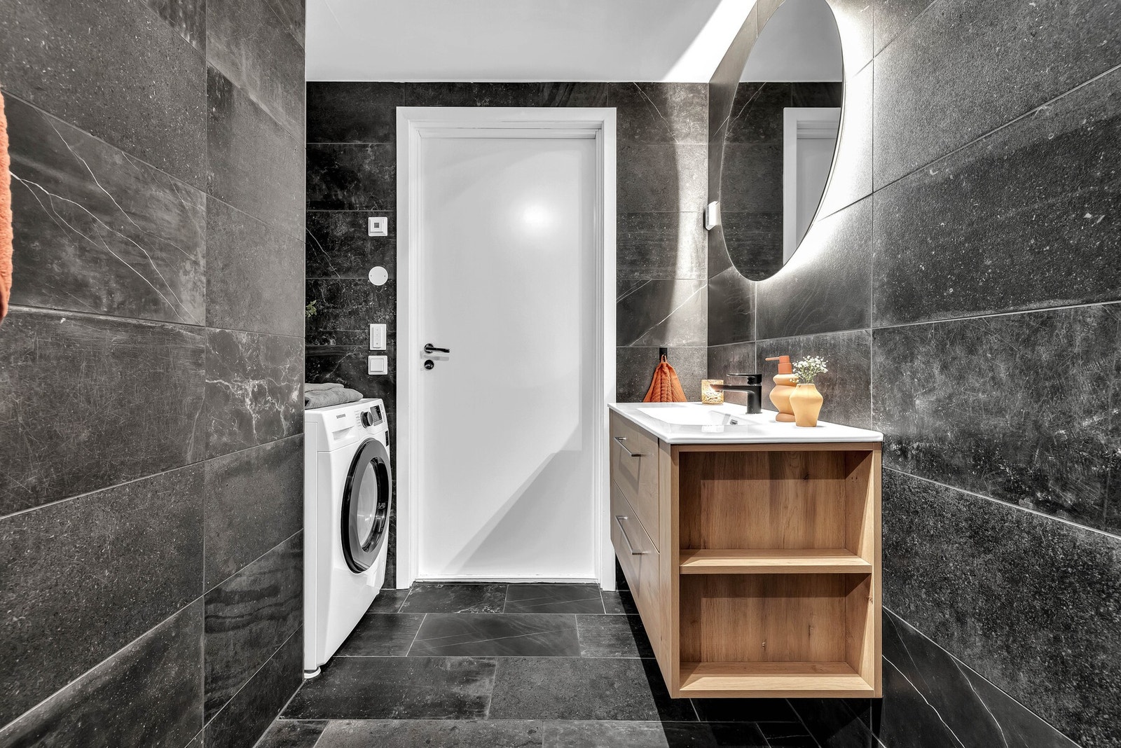 Badet har en egen nisje for plassering av vaskemaskin og tørketrommel, samt en vegghengt innredning med skuffer i eik. Galleribilde