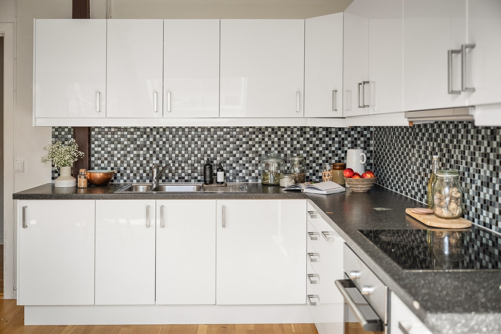 Ikea kjøkkeninnredning med slette fronter, belysning og fliser over laminat benkeplate med oppvaskkum og blandebatteri. Galleribilde