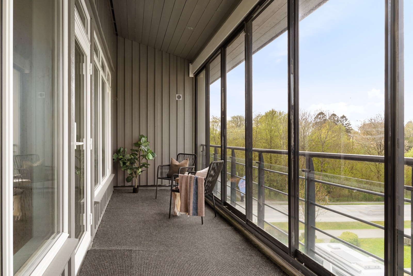 Terrassen har teppelagt dekke og rekkverk i aluminium, og den høye innglassingen kan skyves til side for å slippe inn sommeren på ekstra varme dager Galleribilde