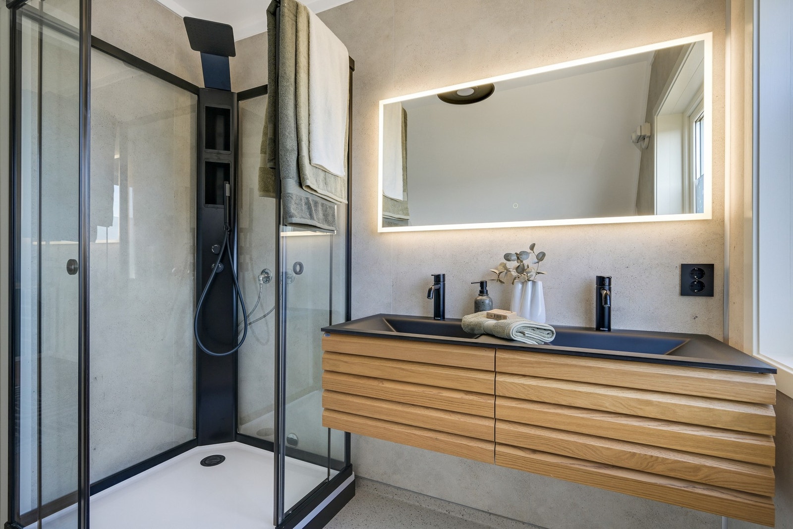Badet inneholder toalett, dobbelservant, speil med lys og dusjkabinett. Galleribilde
