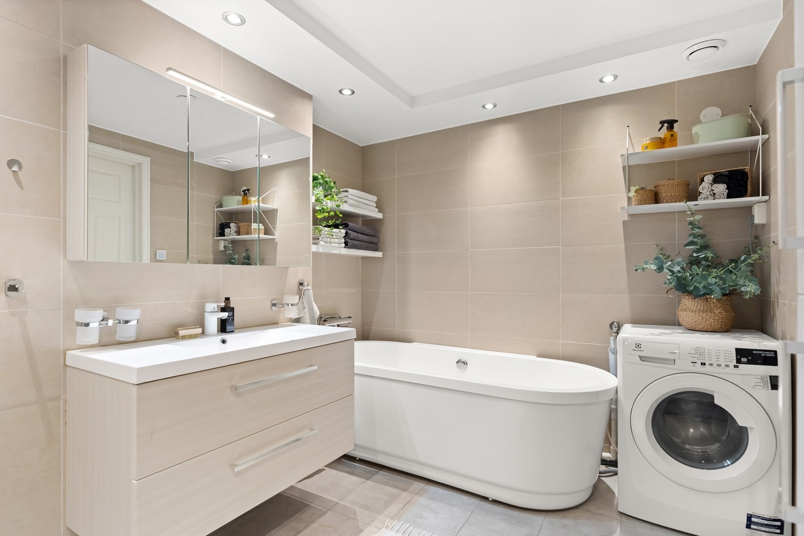 Videre er det opplegg for vaskemaskin, badekar, gulvstående toalett samt et dusjhjørne med svingdører, regnfallsdusj, håndholdt dusj og termostatstyrt blandebatteri. Galleribilde