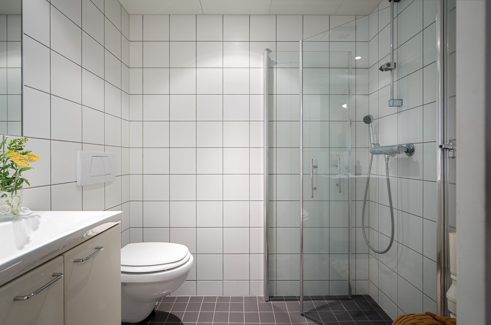 Badet er belagt med lyse fliser på vegger og mørkere kontrastfliser på gulv. Det er lagt varmekabler i gulv. Galleribilde