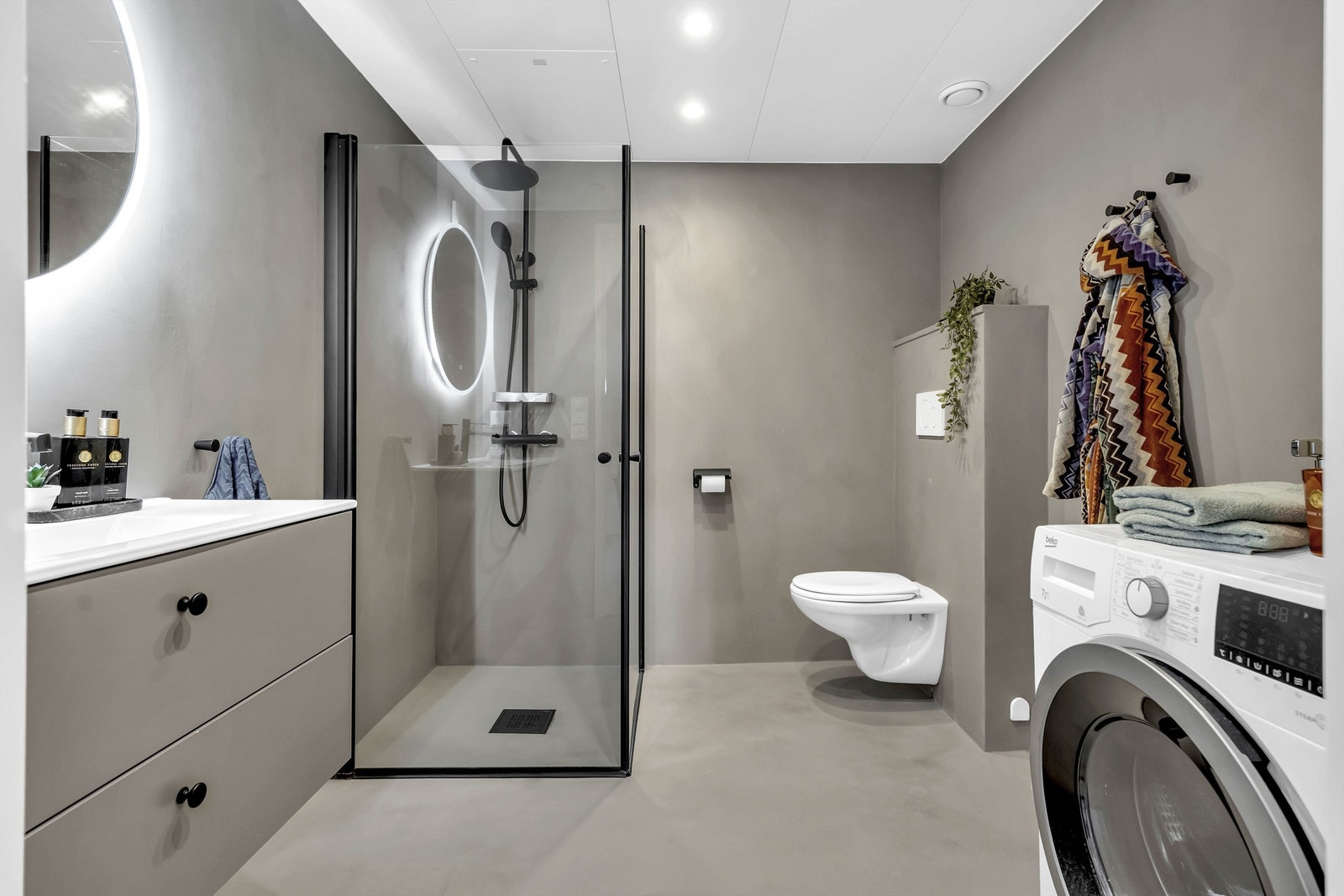 Baderomskabin fra byggeår med beton ciré på vegger og takplater i himling. Badet ble oppgradert med mikrosement og ny baderomsinnredning i 2023. Galleribilde