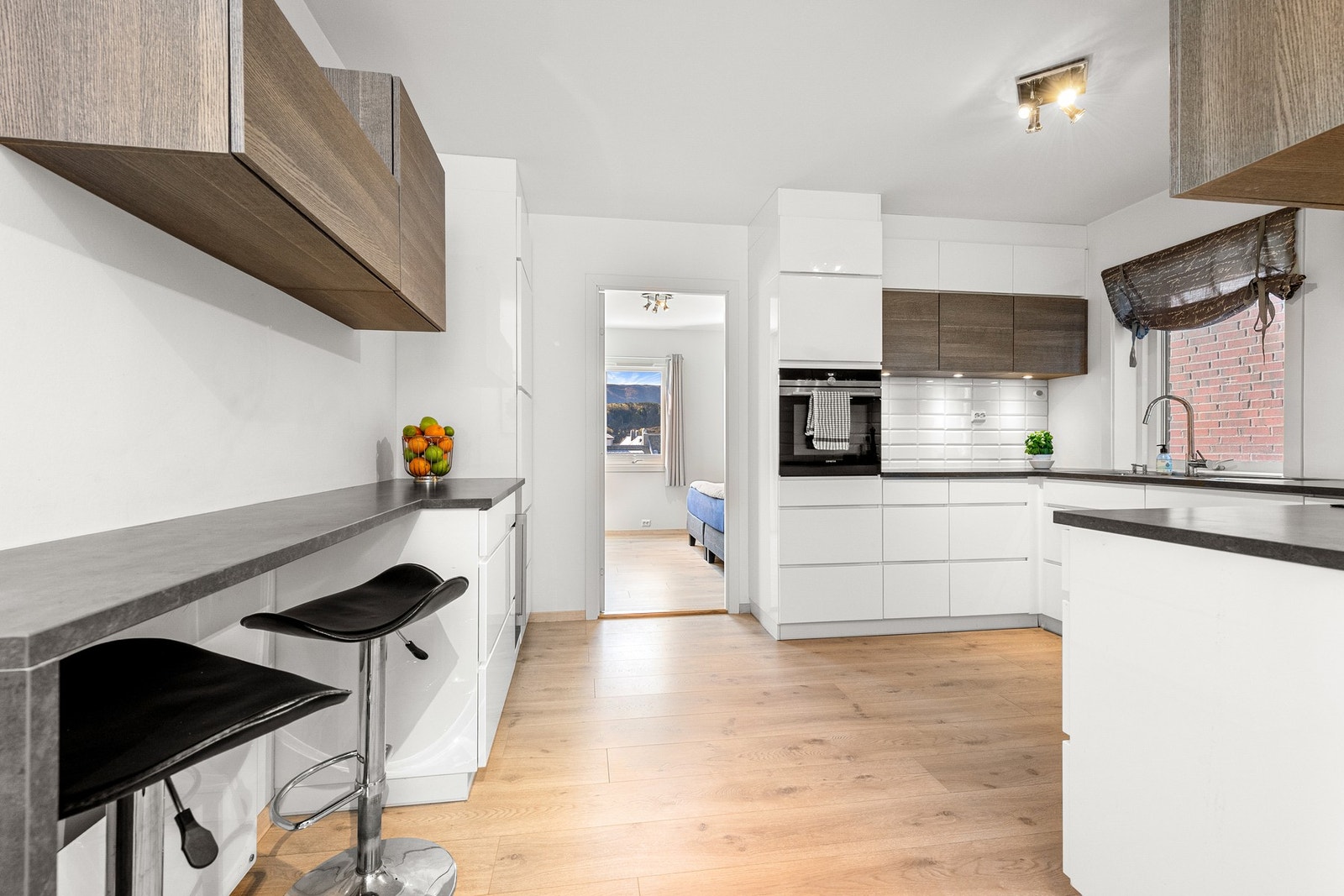 Lys og pen kjøkkeninnredning med brune overskap. Galleribilde