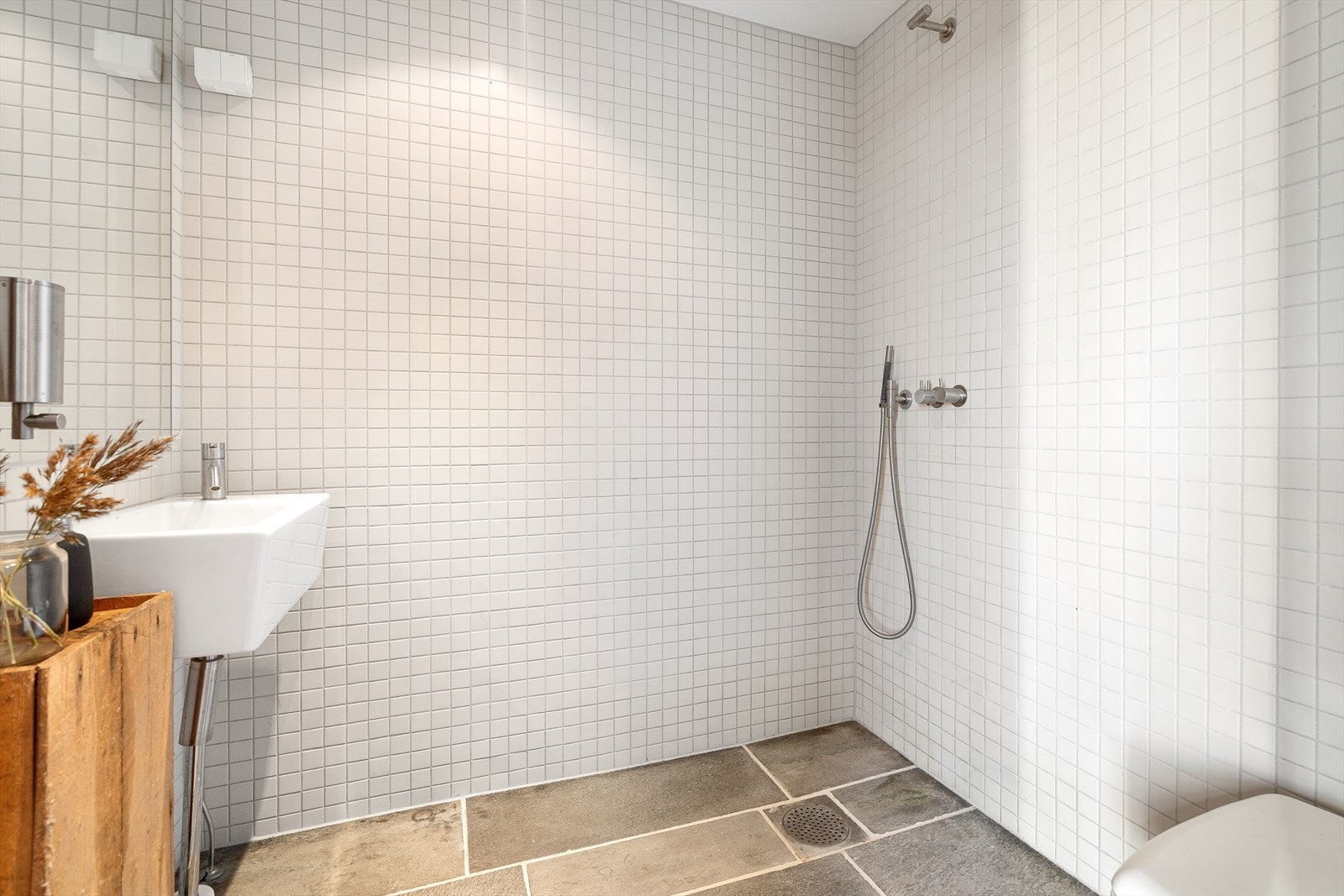 Stilrent baderom med mosaikkfliser på veggene og granittfliser på gulvet. Badet er innredet med snurredo, servant og dusjgarnityr. Galleribilde