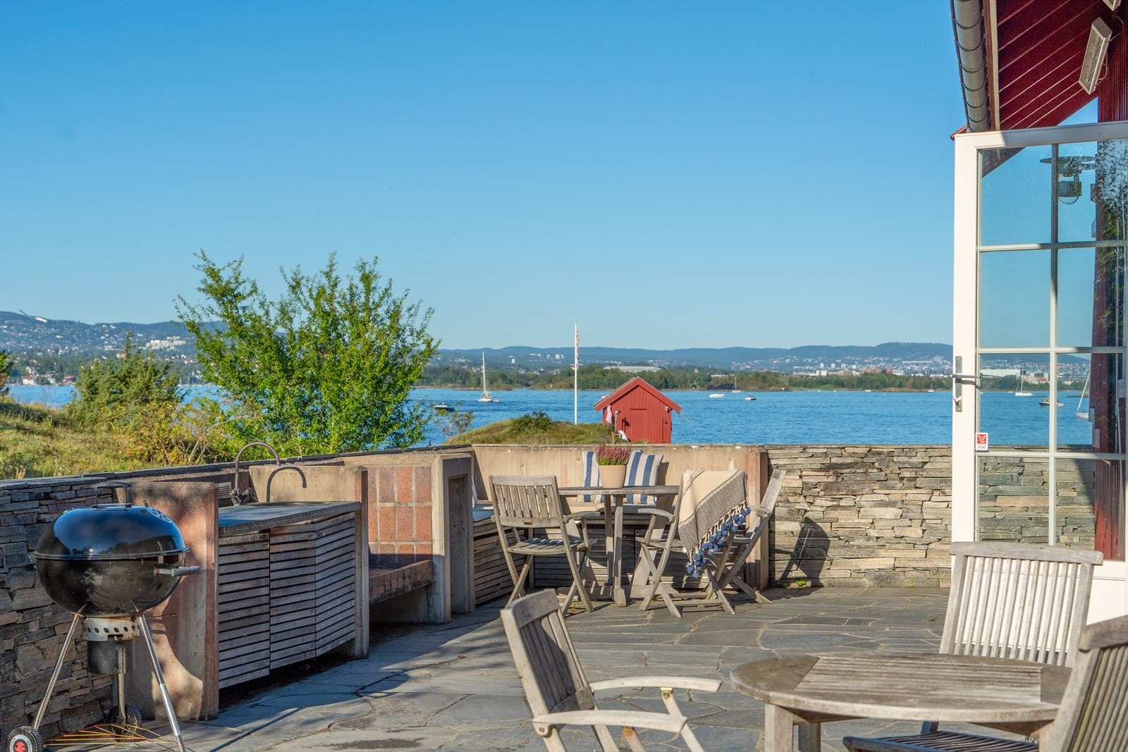 Fritidsboligen har en imponerende skiferbelagt uteplass på ca. 55 m², som tilbyr en enestående utsikt over fjorden. Galleribilde