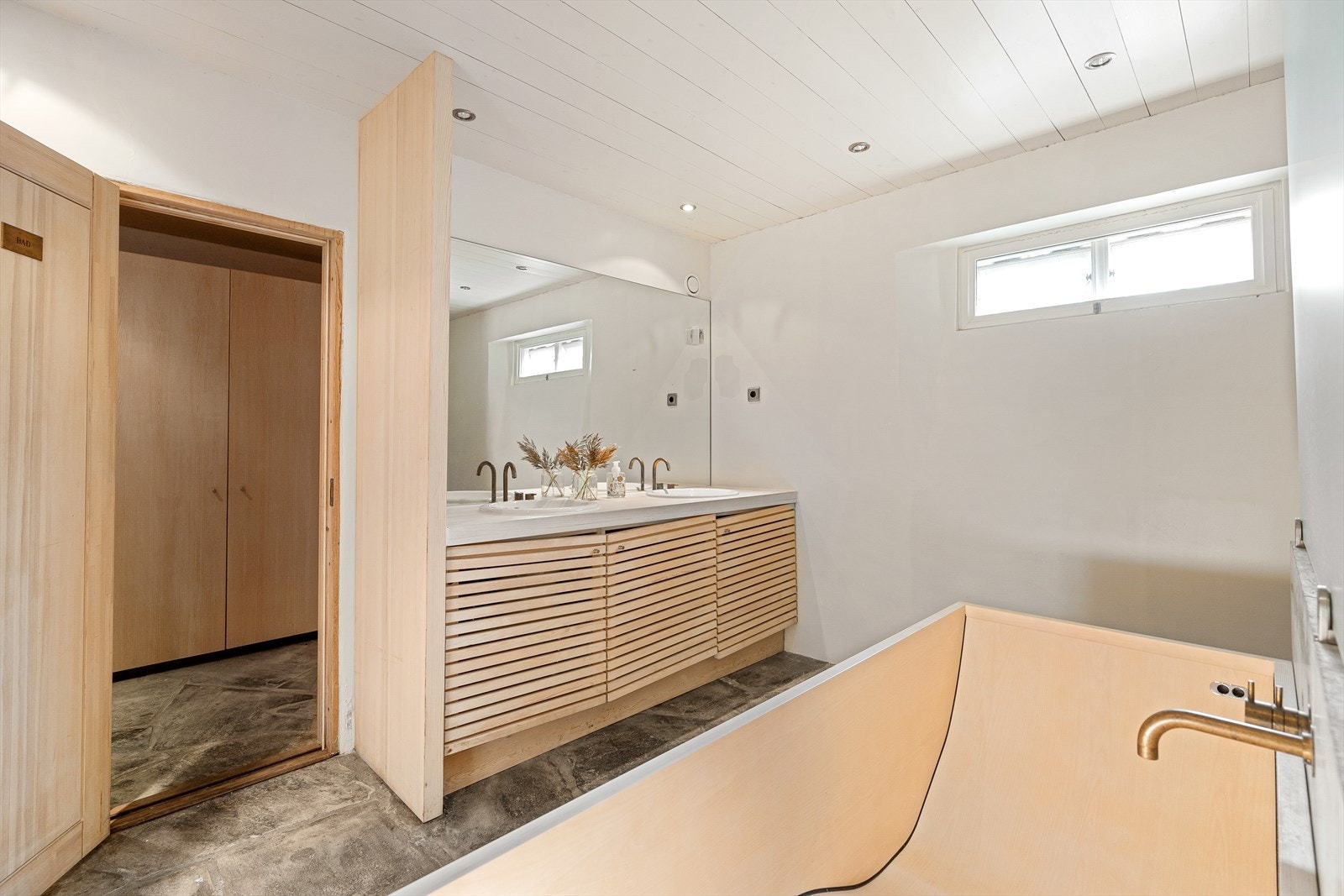 Badet er innredet med dobbel servant i heltre innredning, skapinnredning og dusjnisje. Det er opplegg for vaskemaskin. Galleribilde