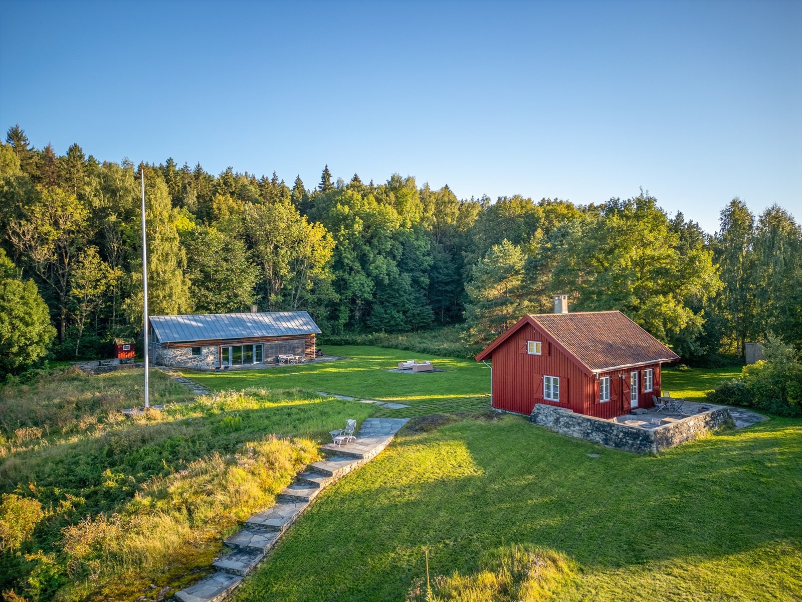 Her finner du en sjarmerende fritidsbolig, et båtnaust for sjøaktiviteter, og en innredet låve som brukes som et ekstra beboelsesrom - perfekt som gjestehus eller for større sammenkomster. Galleribilde